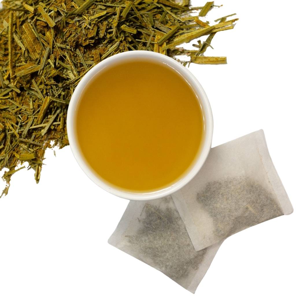 Brewed turmeric lemongrass leaf herbal tea with two tea bags and loose contents of tea bags in upper left hand corner